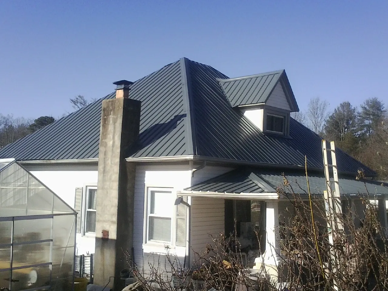 Dark blue standing seam metal roof on a white farmhouse with dormer — Slate & Tile Roof Repair by Roofing Brothers in Chicopee