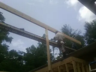 Carpenter setting a ridge beam over a new addition frame — Ice Dam Removal by Roofing Brothers in Chicopee