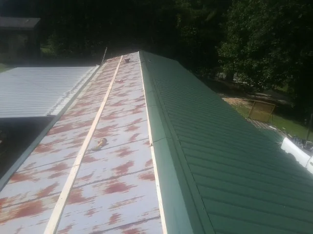 Old rusted panels beside newly installed green metal roofing — Wind Damage Roof Repair by Roofing Brothers in Chicopee