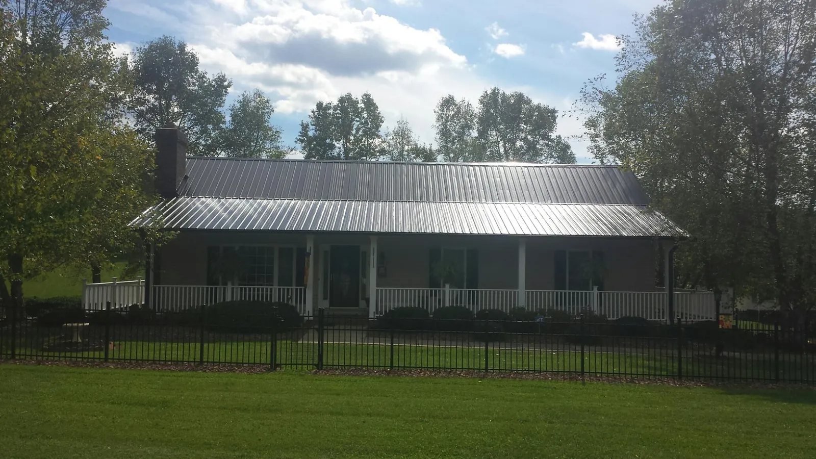 Gray metal roof on a brick ranch with a full width front porch in Chicopee
