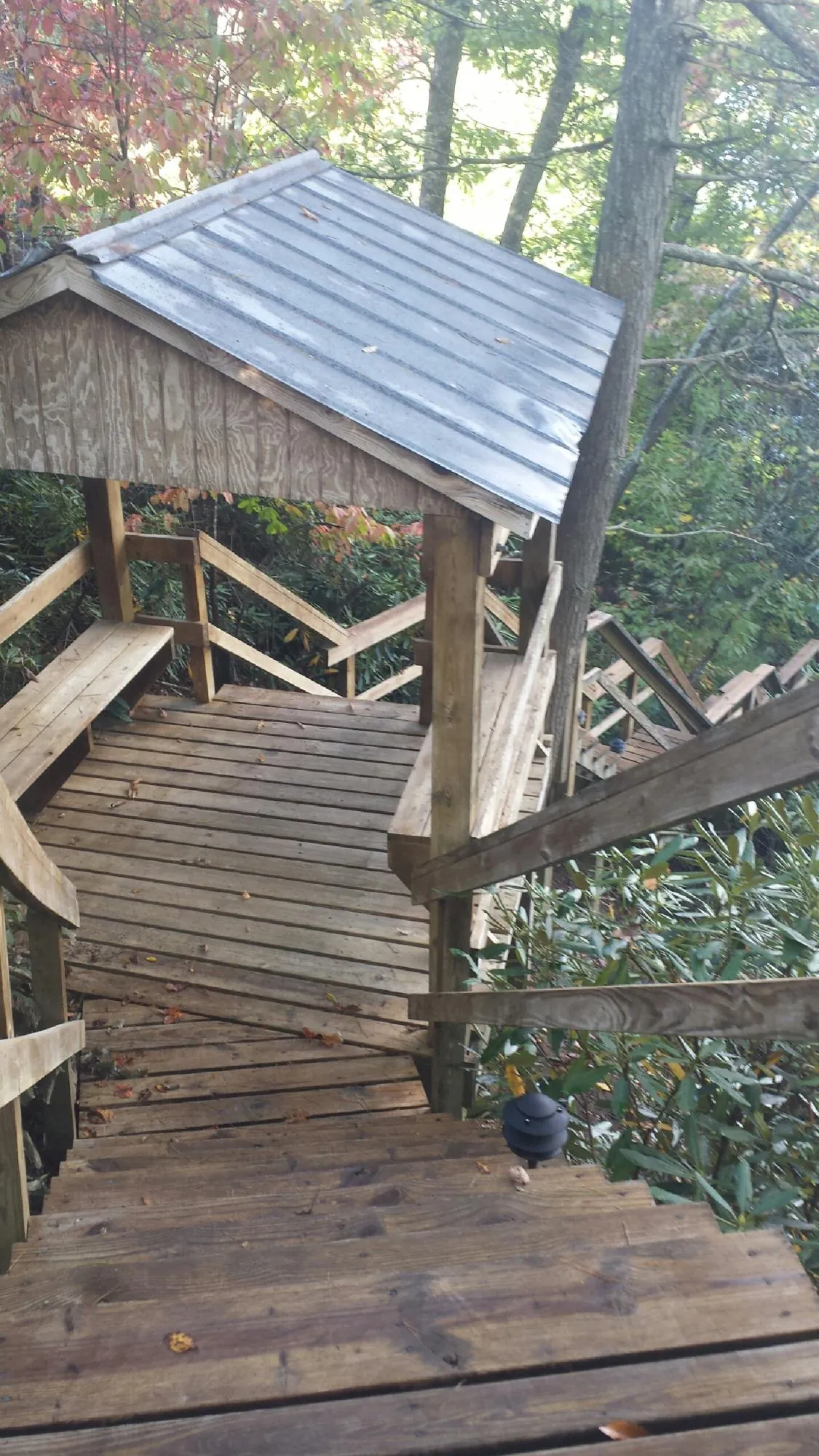 Metal roofed shelter over wooden steps on a wooded walkway — Skylight Repair & Installation work by our crew in Chicopee