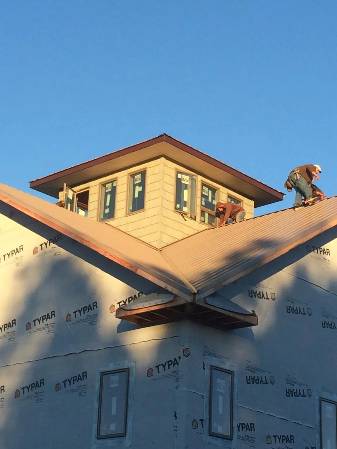 Roofers working around a rooftop cupola on a new metal roof at sunset — Roof Waterproofing in Chicopee by Roofing Brothers